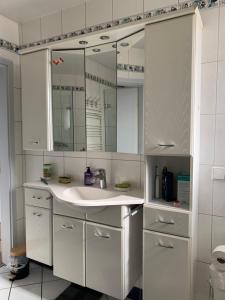 a white bathroom with a sink and a mirror at Appartement dans charmante maison près de Sarrebruck in Grosbliederstroff +18 photos