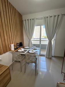 a dining room with a table and chairs and a window at (208)Apt de luxo com varanda 2 quartos 1km do Mar in Tambauzinho