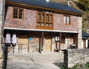 a large brick building with wooden doors and windows at Casa La Farrapona de Babia in Torrestío
