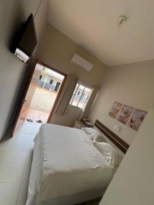 a bedroom with a white bed and a window at Hotel Lupinetti in Jaciara