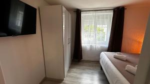 Un dormitorio con una cama y un televisor y una ventana. en Domaine Blue Garden, en Grandvillers