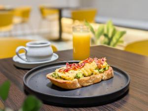 a black plate with a piece of bread and a glass of orange juice at Hotel Attic 33 in Medellín