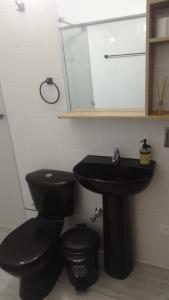 a bathroom with a black toilet and a sink at hotel salome in Puerto Triunfo