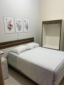 a bedroom with a large white bed with a mirror at Hotel Lupinetti in Jaciara +11 photos