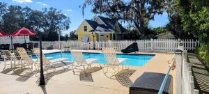 a pool with chairs and a white fence and a house at Shamrock Thistle & Crown B&B in Weirsdale