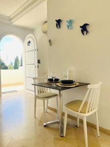 a dining room with a table with two chairs and dolphins on the wall at Maison Douceur in Dar el Ouzir