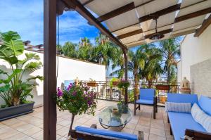 an outdoor patio with blue furniture and palm trees at Casa delle Zammare Fronte mare centro storico in Riposto