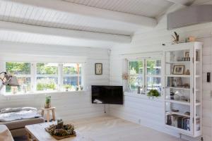 Il comprend un salon doté de murs blancs et d'une télévision à écran plat. dans l'établissement Hear The Sea From Log Cabin In Gilleleje, à Gilleleje