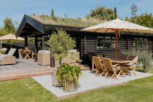 un patio avec une table, des chaises et un parasol dans l'établissement Hear The Sea From Log Cabin In Gilleleje, à Gilleleje