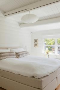 une chambre blanche avec un grand lit et une fenêtre dans l'établissement Hear The Sea From Log Cabin In Gilleleje, à Gilleleje