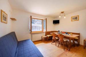a living room with a table and chairs and a couch at Miramonti 21 Ski In - Ski Out - Happy Rentals in Sauze dʼOulx