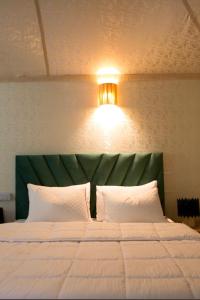 a bed with a green headboard and a light above it at Agafay dreams in Marrakech
