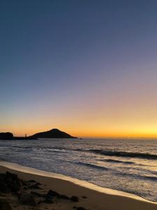 a sunset on the beach with a mountain in the background at Marina del Sol Resort Condo directly on the Ocean 102 in Mazatlán