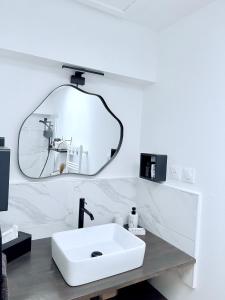 een badkamer met een witte wastafel en een spiegel bij L'Echappée REmily - La Rochelle - proche Ile de Ré in La Rochelle