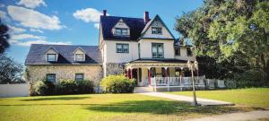 a large white house with a porch on a lawn at Shamrock Thistle & Crown B&B in Weirsdale