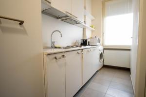 a white kitchen with a sink and a dishwasher at Piacenza centro in Piacenza +16 photos