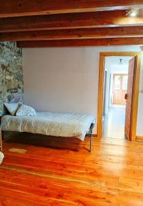 a bedroom with a bed in a room with wooden floors at Casa La Farrapona de Babia in Torrestío