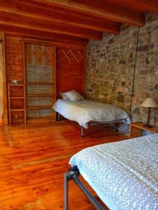 a bedroom with two beds and a stone wall at Casa La Farrapona de Babia in Torrestío