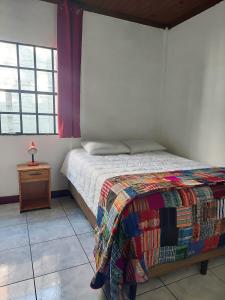 a bedroom with a bed and a table with a bedspread at El Aguacatal in Panajachel