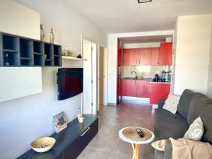 a living room with a couch and a kitchen with red cabinets at Costamar Infinite Sea Views by Deihu Experiences in Los Cristianos