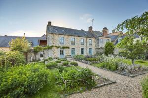 an old stone house with a garden in front of it at Studio cosy proche étang et commerces in Saint-Aubin-du-Cormier