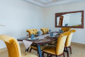 einen Esstisch mit gelben Stühlen und einem Spiegel in der Unterkunft The Crest Apartment in Kigali