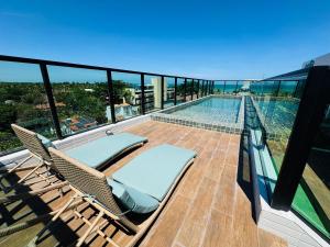 a balcony with a chair and a swimming pool at Mahrak Villa - VSH in Porto De Galinhas