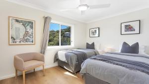 a bedroom with two beds and a chair and a window at Jean's Beach House Accom Holidays in Copacabana