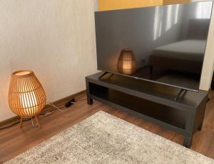 a black entertainment center with a tv and a lamp at Karula Stay - 1 Room City Apartment in Antsla +2 photos