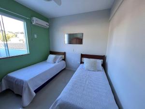 2 Betten in einem Zimmer mit grünen Wänden und einem Fenster in der Unterkunft Residencial Açores in Bombinhas + 67 Fotos