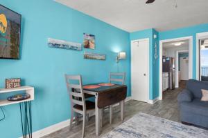 a living room with a table and a blue wall at Palms Resort 905- Oceanfront in Myrtle Beach +13 photos
