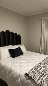 Schlafzimmer mit einem großen weißen Bett mit einem schwarzen Kopfteil in der Unterkunft Unmatched Stays in Kempton Park