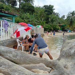a group of people sitting on a beach with umbrellas at Nilka sunset house in Colón