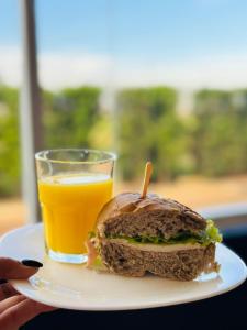 a plate with a sandwich and a glass of orange juice at Hotel Ibis Tatui in Tatuí
