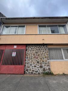 a building with a red door and a stone wall at Hostal Raizén in Temuco +7 photos