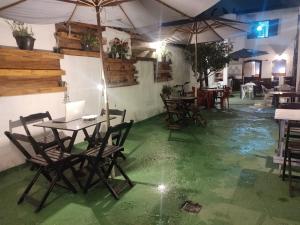 パラチにあるPousada Dádiva Suite Romântica 30 mts da praia Pontal Central com ar e frigobarの緑の床とテーブルとパラソルのあるレストラン