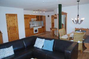 een woonkamer met een zwarte bank en een keuken bij Rügen in Dargun