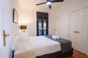 een witte slaapkamer met een bed en een plafondventilator bij Surry Hills Cottage in Sydney