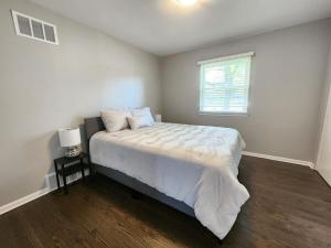 ein Schlafzimmer mit einem Bett mit weißen Laken und einem Fenster in der Unterkunft Naperville Gem in Naperville