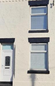 tres ventanas en un edificio de ladrillo con contraventanas azules en Caftop Homes Manchester, en Mánchester