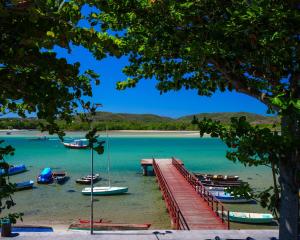 a dock with boats in the water next to a beach at Apê da Lêda Loft - 400m da Praia do Forte in Cabo Frio