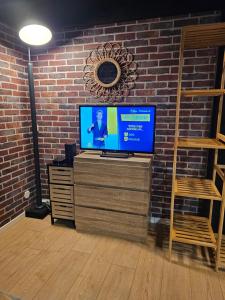 a television on a stand in a room with a brick wall at Duplex à 15 min à pieds de la gare, centre historique Montluçon in Montluçon