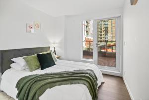 a white bedroom with a bed and a window at Stylish 2 Bed Condo Near Transit and Amenities in East Hastings in Vancouver