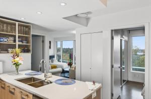 a kitchen with a sink and a living room at Stylish 2 Bed Condo Near Transit and Amenities in East Hastings in Vancouver