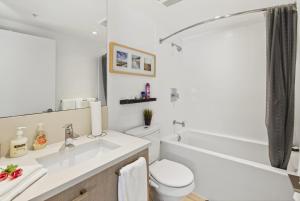 a bathroom with a sink and a toilet and a tub at Stylish 2 Bed Condo Near Transit and Amenities in East Hastings in Vancouver