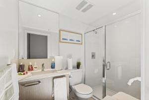 a white bathroom with a toilet and a shower at Stylish 2 Bed Condo Near Transit and Amenities in East Hastings in Vancouver