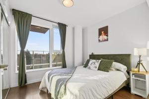 a bedroom with a bed and a large window at Stylish 2 Bed Condo Near Transit and Amenities in East Hastings in Vancouver