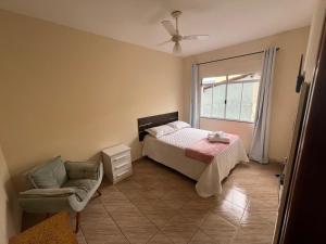 a bedroom with a bed and a chair and a window at Cantinho do Sossego - Piscina com Hidro! in São Lourenço