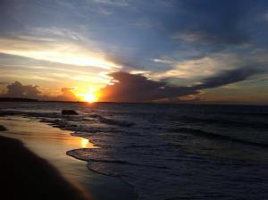 a sunset on the beach with the ocean at Pousada Brisa Do Pontal in Fortim