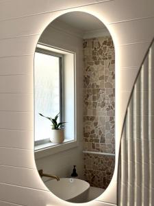 ein Bad mit einem runden Spiegel und einem Waschbecken in der Unterkunft Walk to Beach - Coastal Beach House Retreat in Port Willunga + 46 Fotos